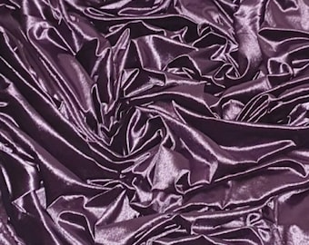 May include: Close-up of a deep purple satin fabric with a soft, luxurious texture. The fabric is draped and folded, creating a dramatic and elegant look.