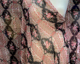 May include: Black sheer fabric with a pink and white floral pattern and a paisley design. The fabric is draped over a white dress form.