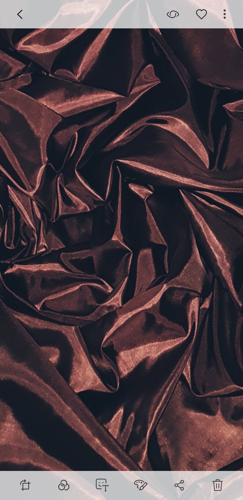 May include: Close-up of a deep burgundy satin fabric with soft folds and wrinkles. The fabric has a luxurious and elegant appearance.