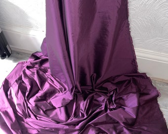 May include: A deep purple taffeta fabric with a smooth, silky texture. The fabric is draped and folded, showcasing its luxurious sheen.