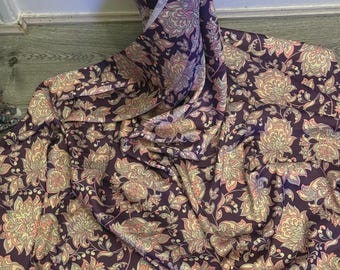 May include: Purple fabric with a floral pattern in shades of pink, yellow, and white.
