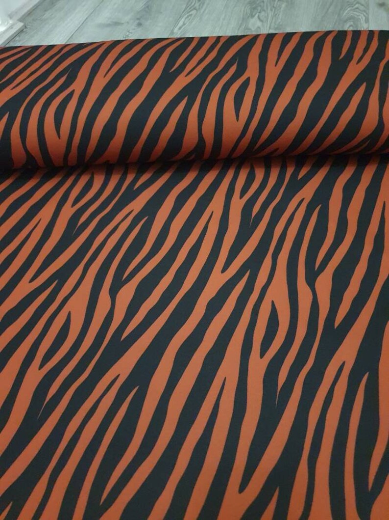 Pu&ograve; includere: Tessuto arancione e nero con motivo a zebre.
