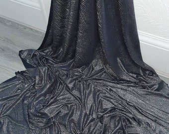May include: Black fabric with a silver shimmer. The fabric is wrinkled and has a textured surface.