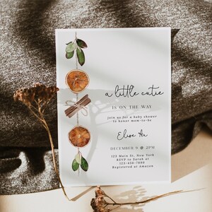 K&ouml;nnte beinhalten: Eine Babyparty-Einladung mit dem Text "a little cutie is on the way". Die Einladung zeigt Aquarellillustrationen von getrockneten Orangenscheiben, Zimtstangen und Gr&uuml;nzeug. Die Details umfassen Datum, Uhrzeit und Ort.