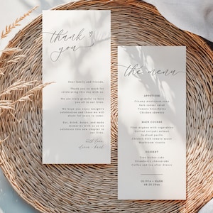 Puede incluir: Dos tarjetas de menú de boda y una tarjeta de agradecimiento con texto de caligrafía sobre un mantel individual tejido. El menú incluye aperitivos, platos principales y opciones de postre. La tarjeta de agradecimiento tiene un mensaje escrito a mano.