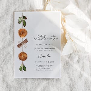 K&ouml;nnte beinhalten: Eine wei&szlig;e Babyparty-Einladung mit dem Text "a little cutie is on the way". Die Einladung ist mit Aquarell-Orangenscheiben, Zimtstangen und Gr&uuml;n dekoriert. Die Details umfassen Datum, Uhrzeit, Ort und RSVP-Informationen.