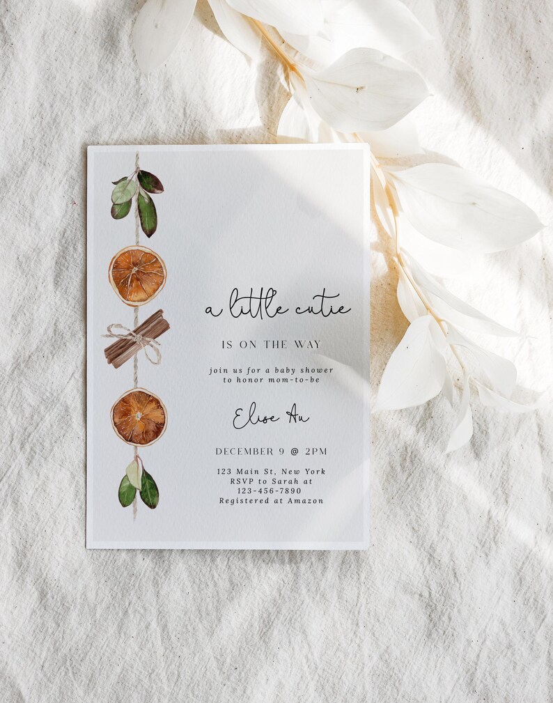 K&ouml;nnte beinhalten: Eine wei&szlig;e Babyparty-Einladung mit dem Text "a little cutie is on the way". Die Einladung ist mit Aquarell-Orangenscheiben, Zimtstangen und Gr&uuml;n dekoriert. Die Details umfassen Datum, Uhrzeit, Ort und RSVP-Informationen.