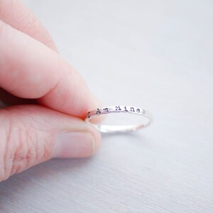 Sterling Silver Stacking Ring handstamped with I Am Mine being held between fingers