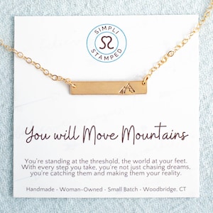 May include: Gold necklace with a bar pendant featuring a mountain silhouette. The necklace comes with a card that reads "You will move mountains" and includes a quote about chasing dreams and making them a reality.