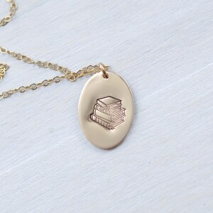 image of gold-filled book lovers necklace stamped with a stack of books