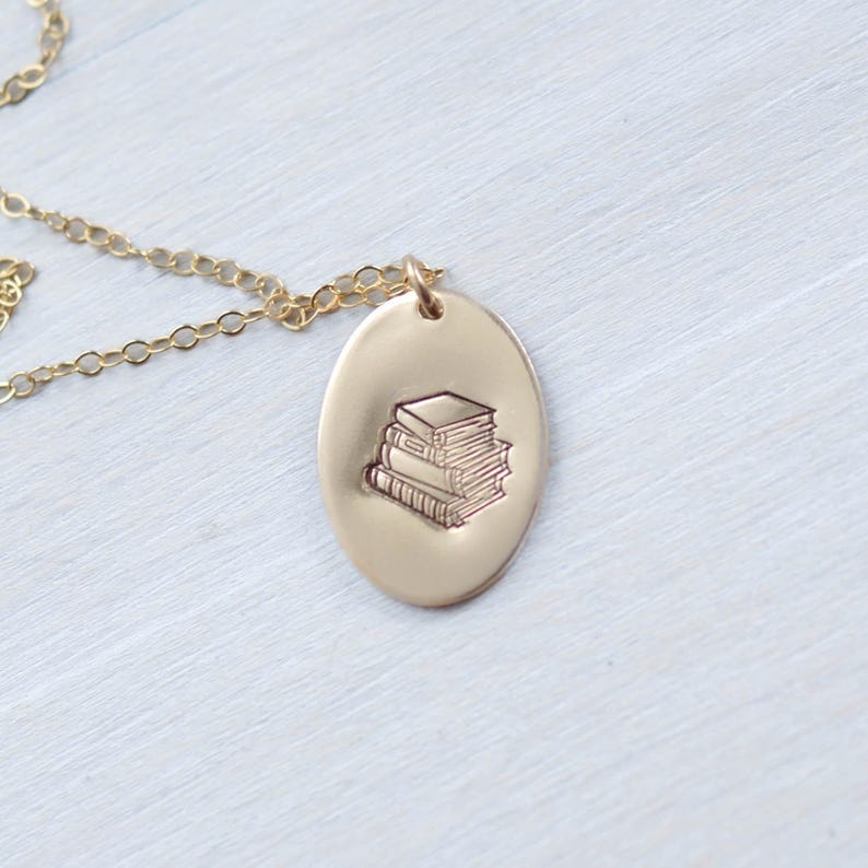 image of gold-filled book lovers necklace stamped with a stack of books