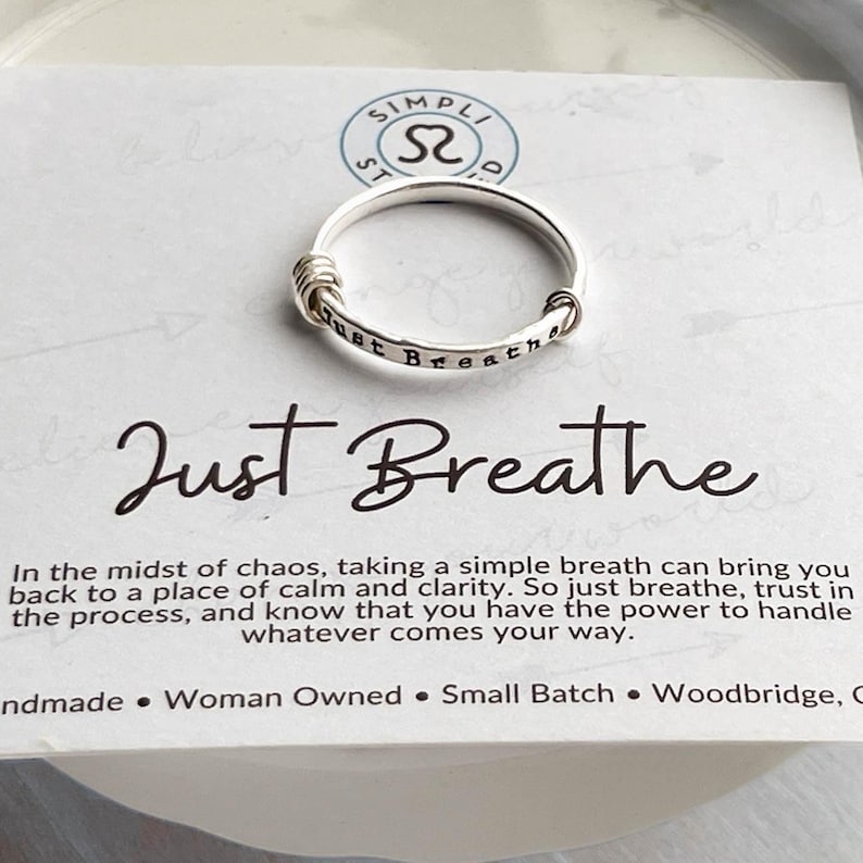 Pu&ograve; includere: Anello d'argento con la scritta "just breathe" incisa sulla fascia. L'anello &egrave; su una carta bianca con la scritta "Just Breathe" in corsivo e un messaggio sulla calma. Fatto a mano.