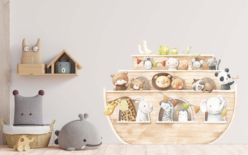 May include: A brown wooden ark with a variety of animals peeking out of the windows. The ark is decorated with colourful flags and a green snake. The ark is on a white wall with a shelf above it.