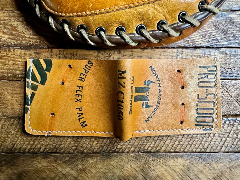 May include: A brown leather baseball glove with white stitching and the text "PRO-SCOOP", "NORTH AMERICAN", "MZ C1050 STEERHIDE", and "SUPER FLEX PALM" printed on it.