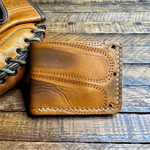 May include: A brown leather wallet with white stitching. The wallet has a worn, distressed look and is made of high-quality leather.