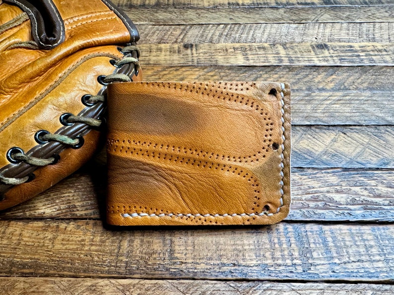May include: A brown leather wallet with white stitching. The wallet has a worn, distressed look and is made of high-quality leather.
