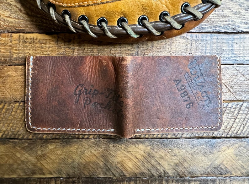 May include: A brown leather wallet with the text "Grip-Tite Pocket" and "Tuf-Nuff Made in U.S.A. 49876" embossed on the front.