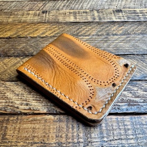 May include: A brown leather wallet with white stitching and a distressed look. The wallet has a flap closure and multiple card slots.