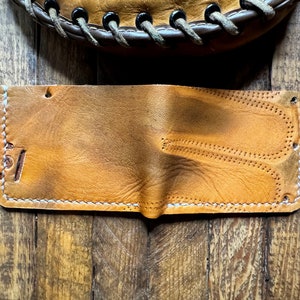 May include: A brown leather wallet with white stitching and a small "51" embossed on the front.