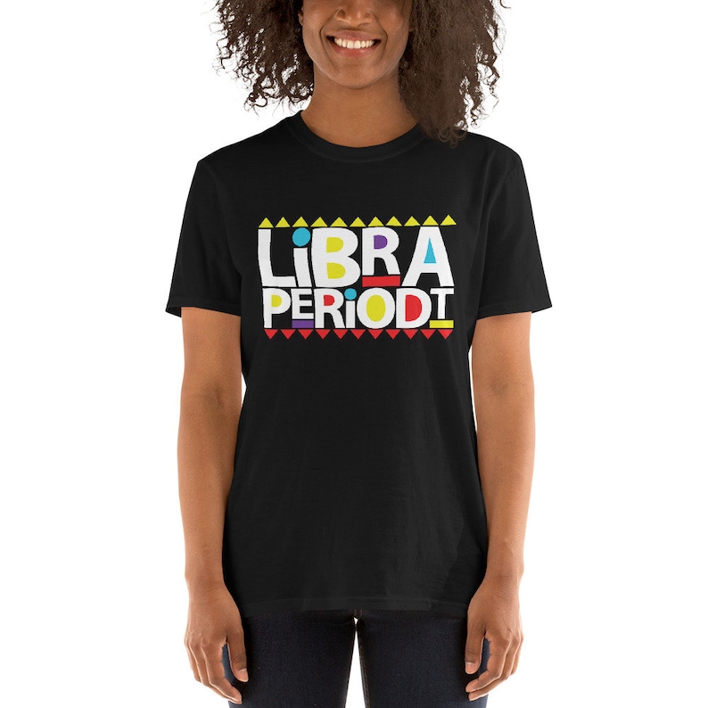 Puede incluir: Camiseta negra con un gr&aacute;fico blanco que dice "LIBRA PERIODT" en letras may&uacute;sculas de colores con un patr&oacute;n geom&eacute;trico amarillo, rojo y azul.