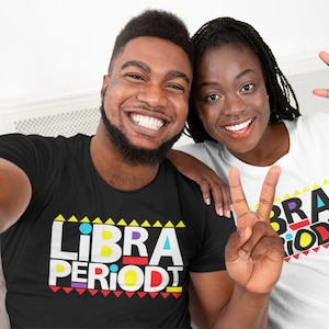 Puede incluir: Dos personas con camisetas negras y blancas con el texto "LIBRA PERIODT" en letras de bloque de colores. La persona de la izquierda lleva una camiseta negra y la persona de la derecha lleva una camiseta blanca.