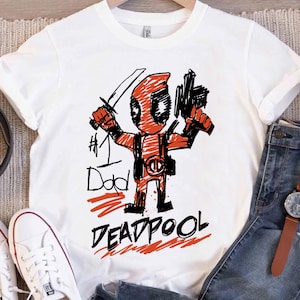 May include: A white ceramic mug with a black handle and the text "But first, coffee" in a black, handwritten-style font. The mug is on a white surface.