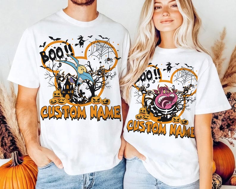 May include: Two white short-sleeve t-shirts featuring a Halloween-themed graphic. The design includes a mouse-ear silhouette, a spider web, bats, a witch, pumpkins, and the text "BOO!!" and "CUSTOM NAME" in orange, black, and purple colors.