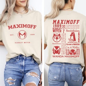 Puede incluir: Camiseta beige con texto y gráficos rojos. La parte delantera presenta "MAXIMOFF" sobre un logotipo "M" estilizado y "SCARLET WITCH" debajo. La parte trasera tiene "MAXIMOFF 1989 SCARLET WITCH" con citas e imágenes de la serie WandaVision.