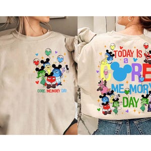 May include: Beige sweatshirt with a colourful graphic of animated characters holding balloons. The front of the sweatshirt reads "CORE MEMORY DAY." The back of the sweatshirt has the text "TODAY IS A CORE MEMORY DAY."