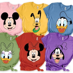 以下が含まれることがあります： さまざまな色の半袖Tシャツ6枚のコレクションで、それぞれ異なる漫画のキャラクターの顔が描かれています。シャツの色はピンク、イエロー、ブルー、グリーン、レッド、パープルです。漫画のキャラクターには、ミッキーマウス、プルート、ドナルドダック、デイジーダック、ミニーマウス、グーフィーが含まれます。