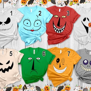 以下が含まれることがあります： 8枚の半袖Tシャツのコレクション。それぞれ異なるキャラクターの顔が描かれています。Tシャツには1から8までの番号が振られており、縫い合わされた口や大きな笑顔など、それぞれ特徴的な表情がプリントされています。