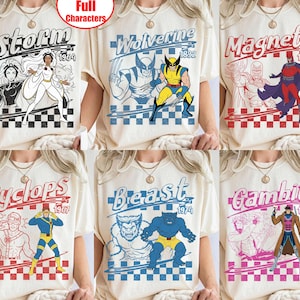 Peut inclure: Un t-shirt crème avec une impression graphique de personnages X-Men, dont Storm, Wolverine, Magneto, Cyclops, Beast et Gambit. Chaque personnage est affiché avec son nom, une année et un arrière-plan à motif en damier.