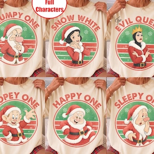 May include: A collection of six cream-coloured t-shirts featuring Disney characters in Santa outfits within circular frames. Designs include Grumpy, Snow White, The Evil Queen, Dopey, Happy, and Sleepy, each with their name printed in red text.