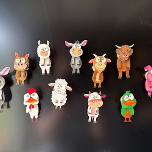 May include: A collection of eleven wooden animal magnets featuring a donkey, horse, llama, goat, highland cow, pig, chicken, sheep, cow, and duck. Each animal is rendered in a cartoon style with distinct colors, including brown, white, gray, pink, and green, designed for attachment to a magnetic surface.