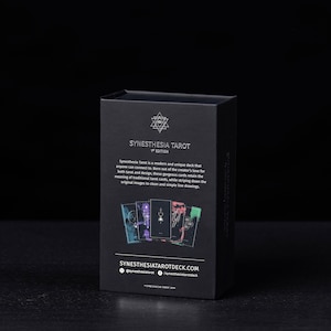 May include: Black box with a silver design and text that reads "Synesthesia Tarot 1st Edition". The box features a description of the tarot deck and the website address "synesthesiatarotdeck.com".