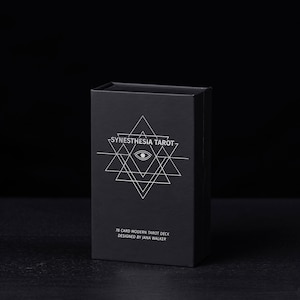 May include: A black box with a white geometric design and the text "Synesthesia Tarot" on the front. The box also includes the text "78 Card Modern Tarot Deck Designed by Jana Walker".