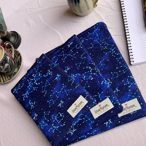 May include: Three blue fabric pouches with a constellation pattern and gold stars. Each pouch has a white label with the text "Star Keeper Handmade".