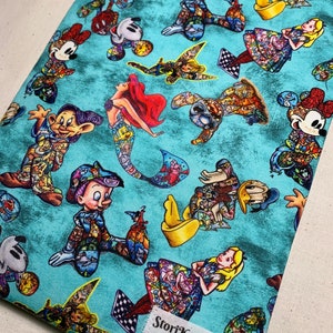 May include: A turquoise blue fabric with a repeating pattern of Disney characters. The characters are all in a cartoon style and are wearing different outfits. The fabric has a distressed look and the characters are all in a variety of poses. The fabric has the text "StoriKeeper" in the bottom right corner.