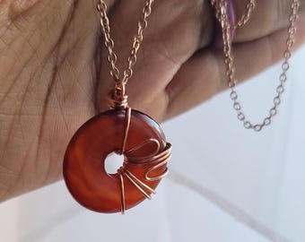 May include: A copper chain necklace with a carnelian stone pendant wrapped in copper wire.