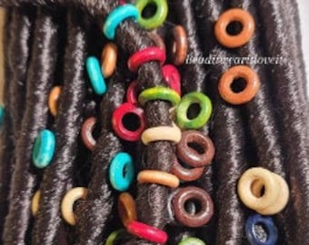 May include: Close-up of brown synthetic dreadlocks with colorful wooden beads and rings. The beads are in various colors, including red, blue, green, and brown.