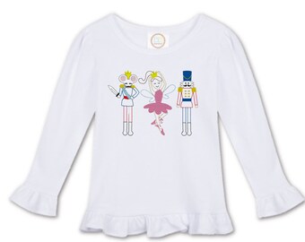 Könnte beinhalten: Weißes Langarmshirt mit Rüschen am Saum. Das Shirt zeigt ein gesticktes Design mit einer Maus, einer Ballerina und einem Nussknacker.
