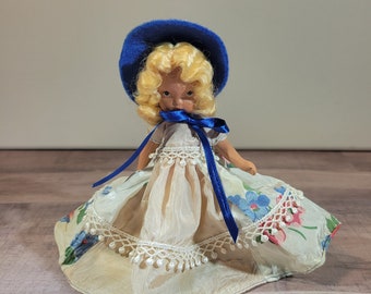Vintage Nancy Ann Puppe, gemalte Augen, geblümtes Kleid, blaue Mütze, Biskuitporzellan Puppe mit gefrorenen Beinen