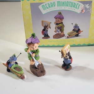 May include: A "Merry Miniatures" 3-piece set featuring miniature figurines of garden gnomes and insects. The figurines are in various poses, including pushing a wheelbarrow and using a shovel. The box reads "Getting Ready for Spring".
