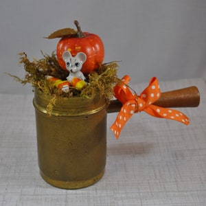 Encantador ratón en una viñeta en miniatura de otoño, calabaza y maíz dulce en una taza de latón y madera vintage