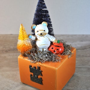 Handcrafted Halloween Miniature Vignette with vintage trick or treating mummy bear, pumpkin, and bottle brush trees