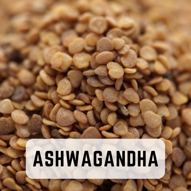May include: Close-up of a pile of light brown ashwagandha seeds. The seeds are small and round, with a slightly rough texture. The text "ASHWAGANDHA" is printed in black on a white rectangle.