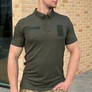 May include: A dark green short-sleeved polo shirt with a button-up collar and two patch pockets on the chest.