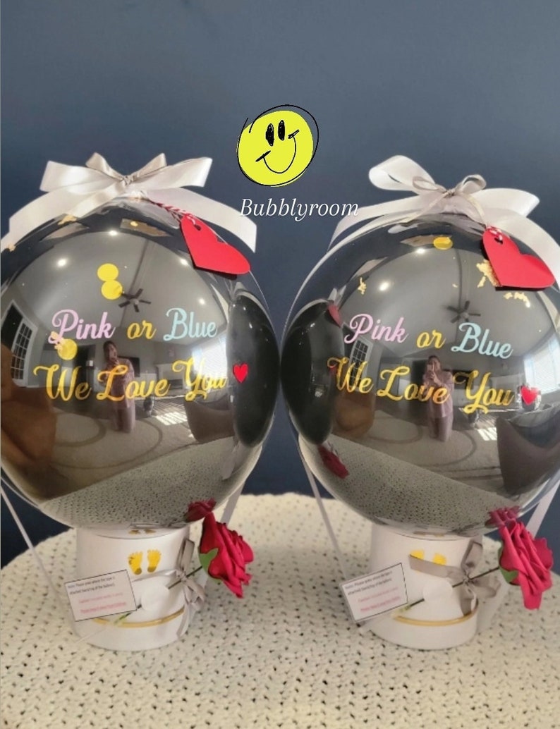 Puede incluir: Dos globos aerost&aacute;ticos negros en forma de globo con cinta blanca y una rosa roja. Los globos est&aacute;n decorados con letras doradas que dicen "Rosa o Azul Te queremos".