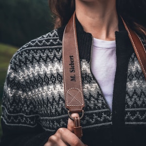 May include: A brown leather camera strap with the name "M. Siebert" engraved on it.