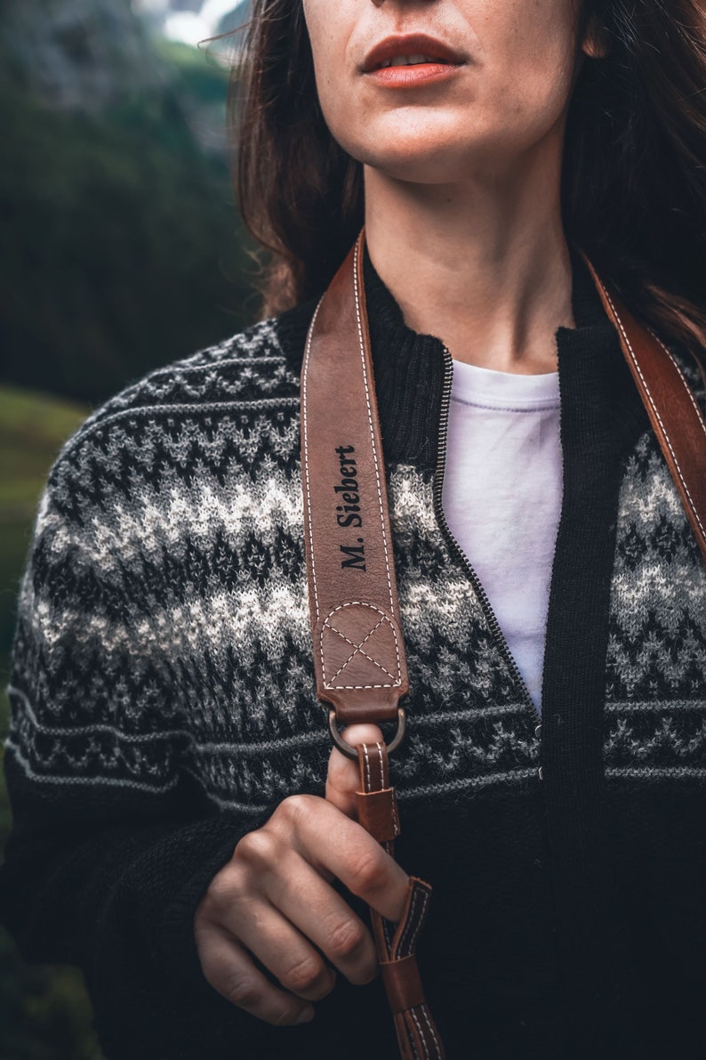 May include: A brown leather camera strap with the name "M. Siebert" engraved on it.